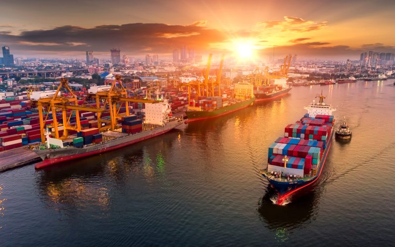 Logistics and transportation of Container Cargo ship and Cargo plane with working crane bridge in shipyard at sunset, logistic import export and transport industry background