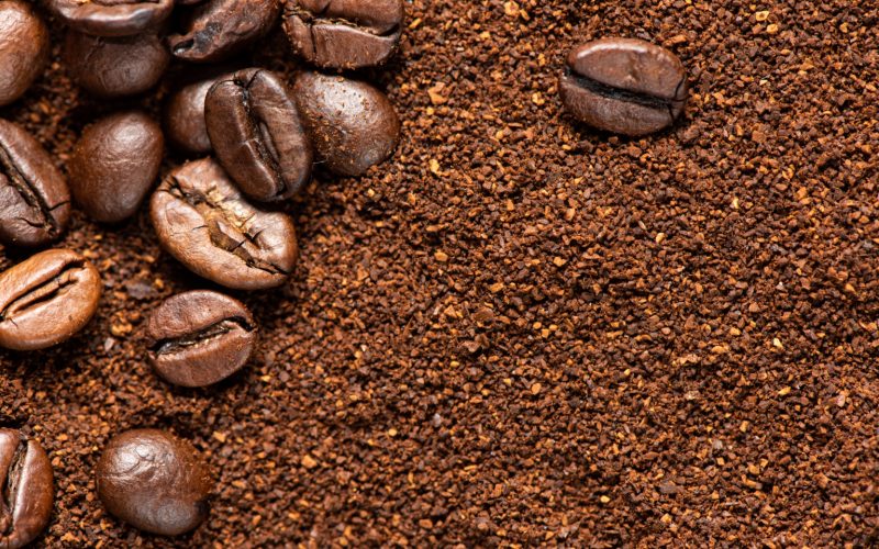 Some coffee beans over ground coffee for coffee theme backgrounds
